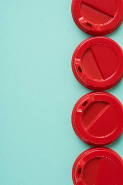 Top view of  four red disposable lids for drink arranged on blue background clipart