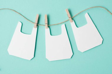 Models of packets hanging on rope on blue background clipart