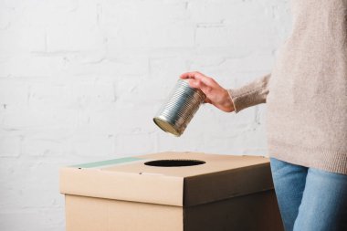 Partial view of woman throwing tin can in trash bin clipart