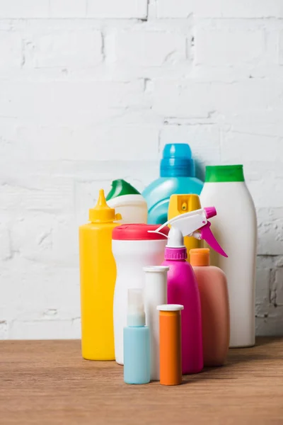 Bouteilles en plastique colorées sur table en bois sur fond mural en brique — Image Bouteilles Plastique Colorées Sur Table Bois Sur Fond Mural Brique Photo De Stock