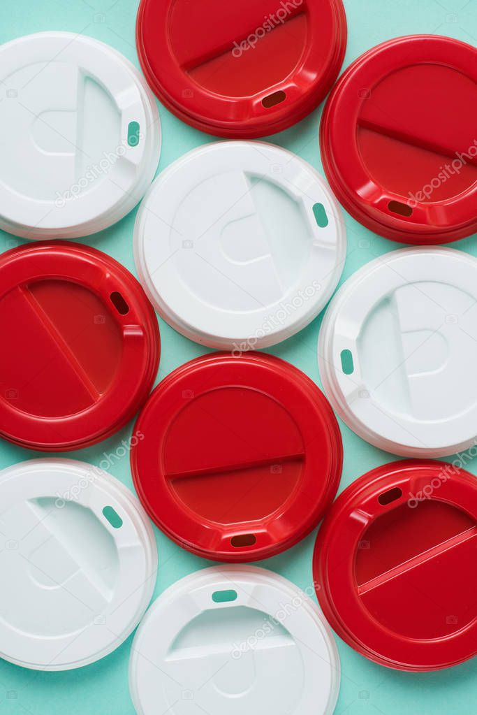 Top view of red and white disposable lids for drink arranged on blue background