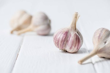 Garlic bulbs on white wooden table clipart