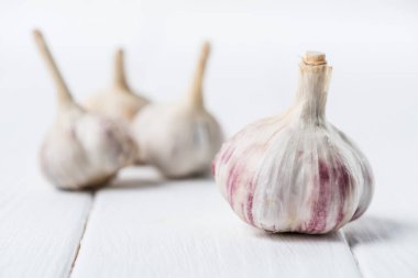 Ripe garlic bulbs on white wooden table clipart