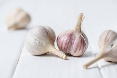 Ripe garlic heads on white wooden table clipart