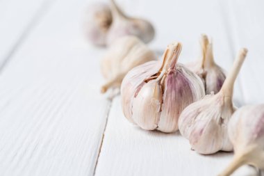 Several ripe garlic bulbs on white rustic table clipart
