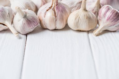 Ripe garlic heads on white rustic cook table clipart