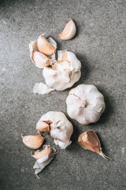 top view of ripe bulbs and cloves of garlic on grey stone table clipart