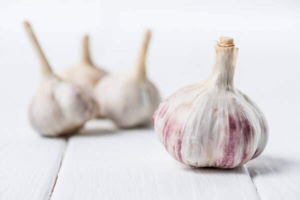 Ripe garlic bulbs on white wooden table