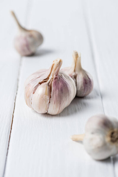 Several garlic bulbs on white wooden table