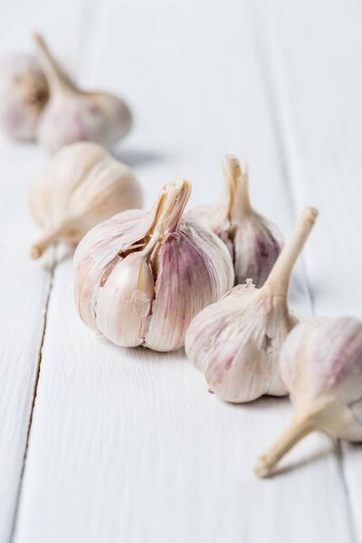 Several ripe garlic heads on white wooden table