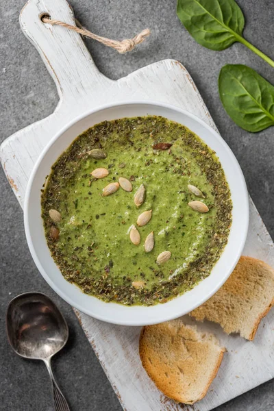 Top view of homemade vegetable creamy soup with slice of bread on cutting board