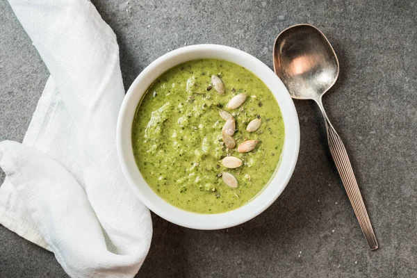 Top view of silver spoon, white cloth and homemade green creamy soup in bowl — Stock Image Top View Silver Spoon White Cloth Homemade Green Creamy Soup Stock Photo