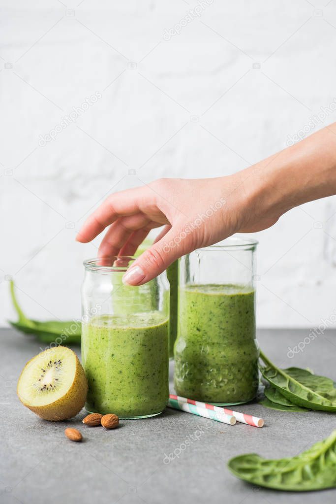 Female hand holding glass with green smoothie