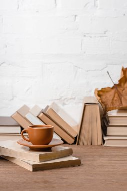 Kitaplar, fincan kahve ve ahşap masa üzerinde kuru sonbahar yaprak