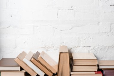 books with hardcovers near white brick wall, educational background