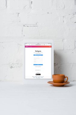Dijital tablet instagram uygulama ve kahve yakınındaki beyaz tuğla duvar ile