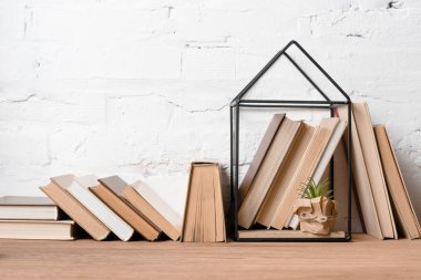 books and green potted plant in house model decoration on wooden table  clipart