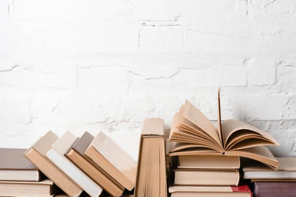 hardcovers beyaz tuğla duvar yakınındaki kitaplarla  