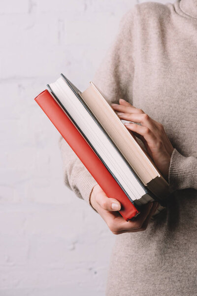 close-up partial view of young woman holding books
