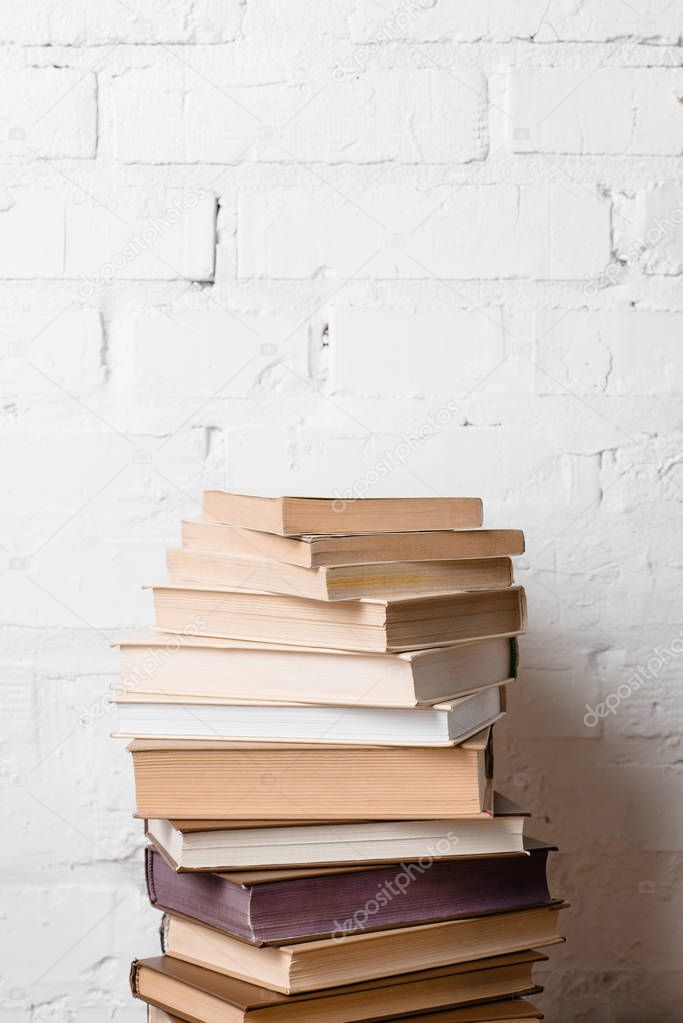 pile of books near white brick wall with copy space