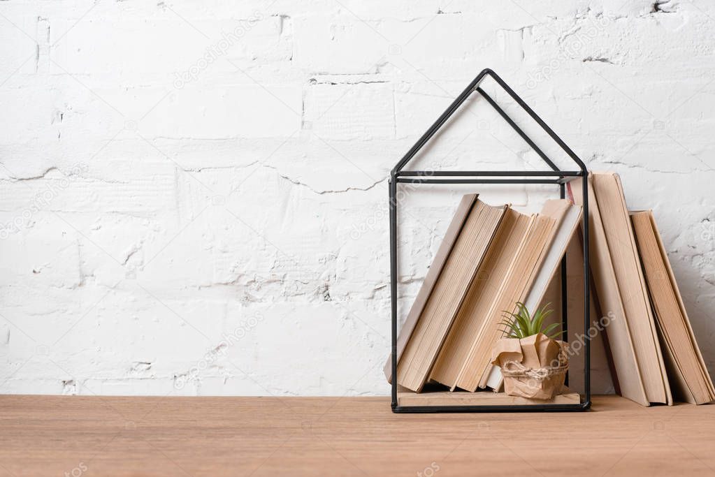 books, green potted plant and house model decoration on wooden table 