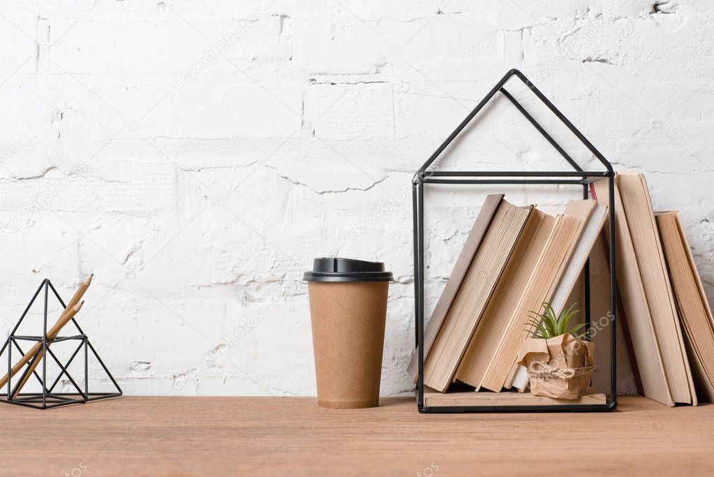 coffee to go, green potted plant and books on wooden table