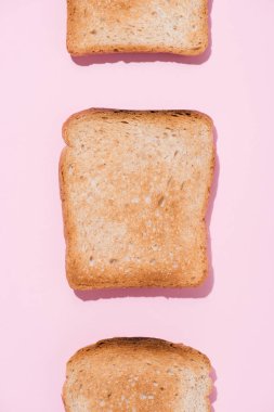 top view of row of crunchy toasts on pink surface clipart