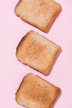top view of row of delicious toasts on pink surface clipart