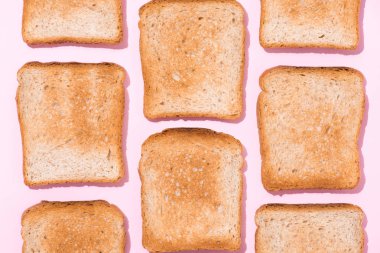 top view of repetitive pattern of crispy toasts on pink surface clipart