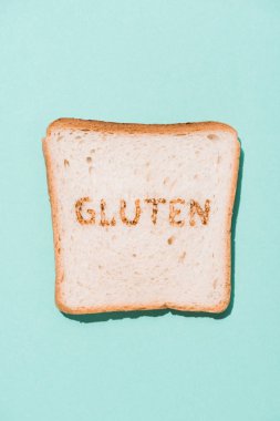 top view of row of bread slice with gluten sign on blue surface clipart