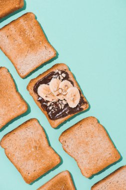 top view of toasts with chocolate paste and banana on blue surface clipart
