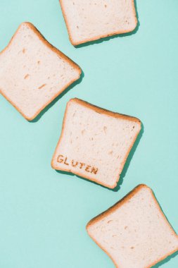 top view of messy spilled bread slices with burned gluten sign on blue surface clipart