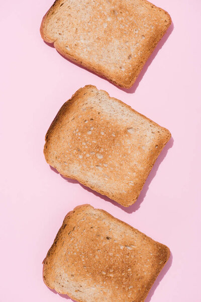 top view of row of delicious toasts on pink surface