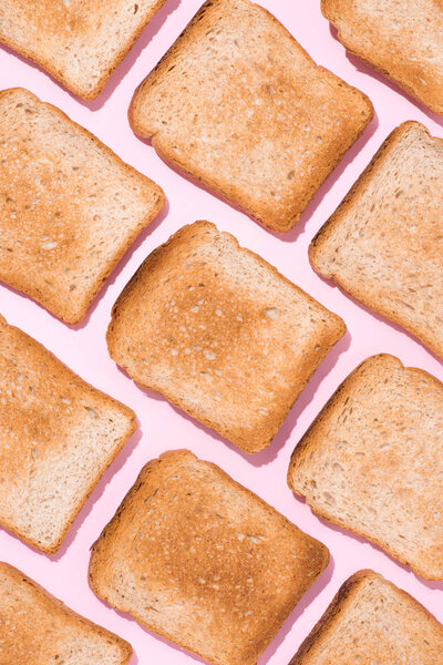 top view of pattern of crunchy toasts on pink surface