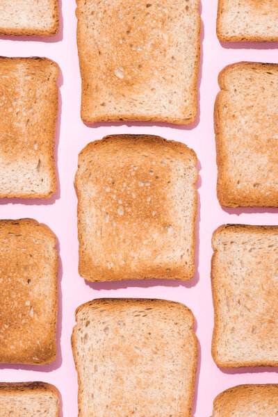 top view of pattern of crispy toasts on pink surface