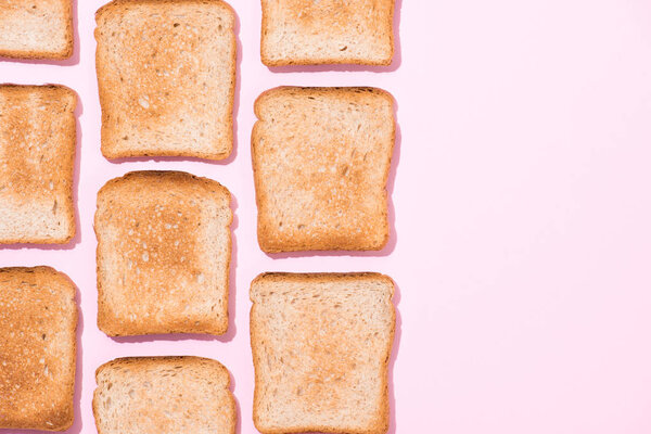 top view of rows of crispy toasts on pink surface