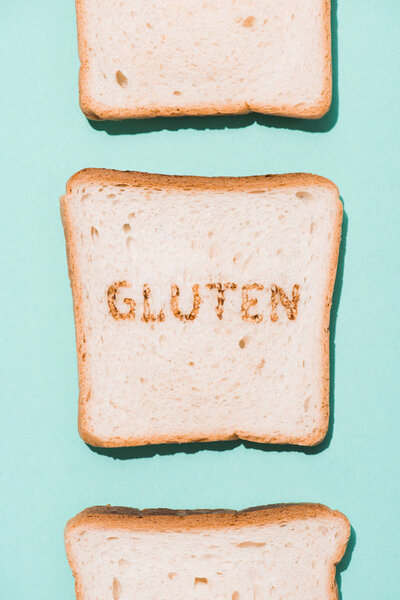 top view of row of bread slices with gluten sign on blue surface