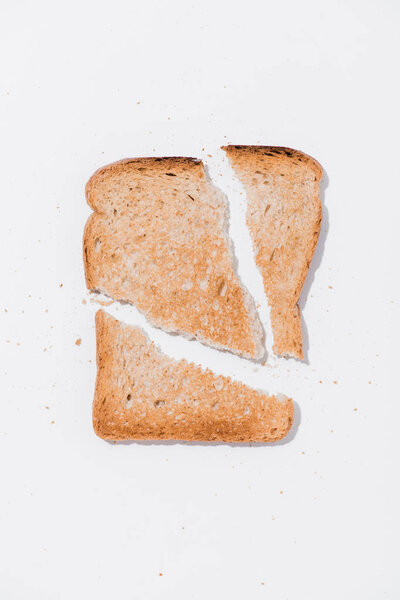 top view of teared toast on white surface