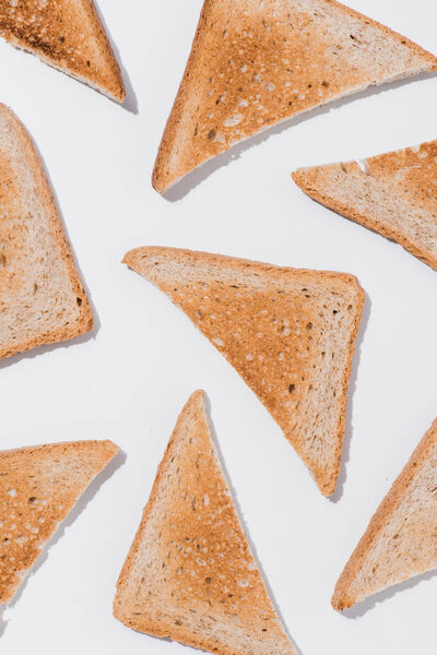 top view of toasts cut in triangles on white surface