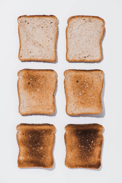 top view of rows of toasts in various roast stages on white surface