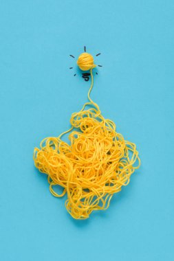 top view of light bulb sign made of yellow yarn on blue background, ideas concept clipart