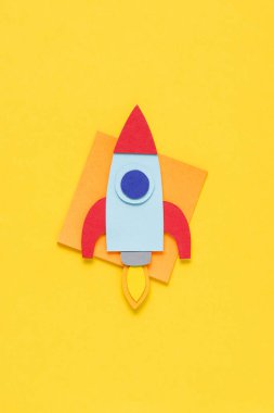 top view of flying paper rocket on yellow background, setting goals concept clipart