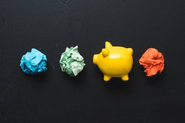 top view of colorful crumpled paper balls with piggy bank on black background, insurance concept clipart