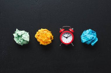 top view of colorful crumpled paper balls and clock on black background, time management concept clipart
