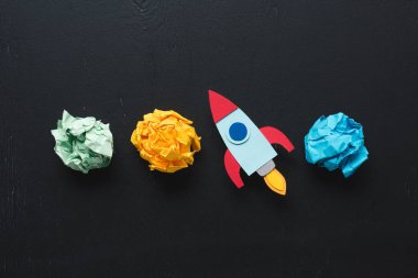 top view of cardboard rocket with crumpled paper balls on black background, setting goals concept clipart