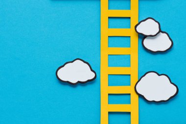 top view of paper ladder with clouds on blue background, setting goals concept