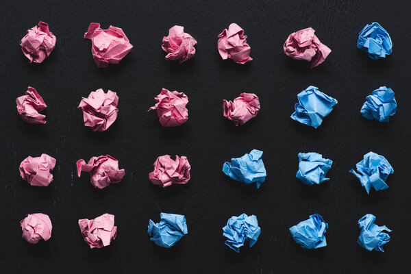 top view of arranged pink and blue crumpled paper balls on black background, think different concept