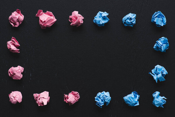 top view of frame made of pink and blue crumpled paper balls on black background, think different concept