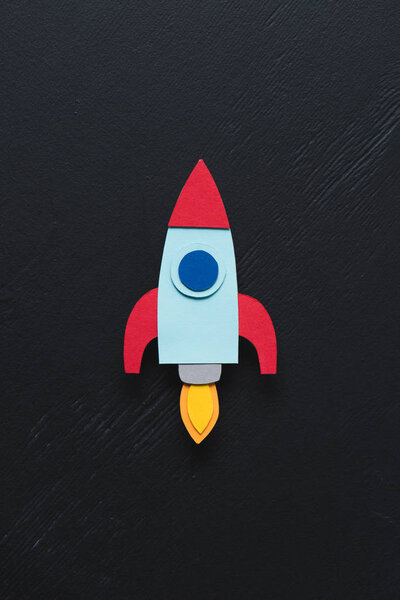 top view of flying paper rocket on black background, setting goals concept