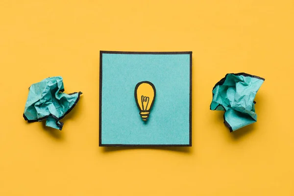 しわくちゃの紙と電球のアイデア コンセプト黄色背景上に描画注意 — ストック写真